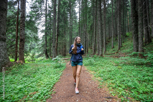 Young smiling woman walking on footpath in the forest