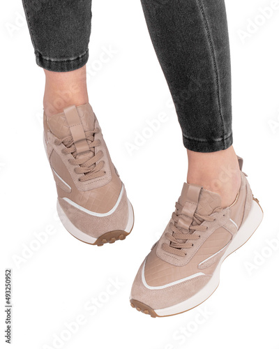 Women's legs in stylish sports shoes on a white background