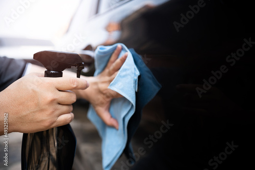 Car clean concept  Hand a man holding clean spray wax and microfiber clenning car body cloth to take care of the surface of the car from washing