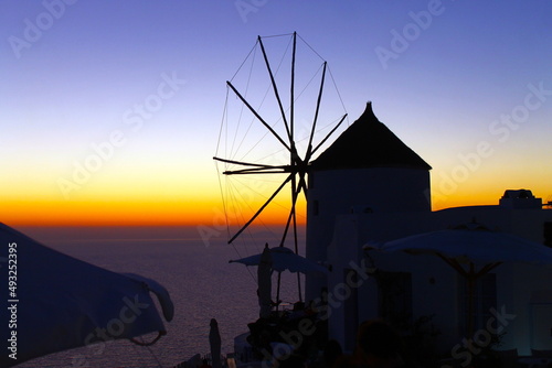 Windmill on sunset with orange and purple sky in Greece