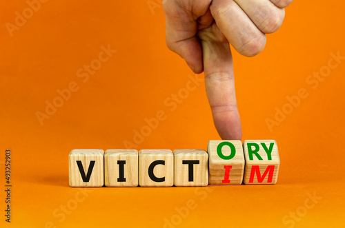 From victim to victory symbol. Businessman turns wooden cubes and changes concept words Victim to Victory. Beautiful orange background. Business support from victim to victory concept. Copy space. photo