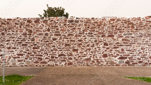 Muro de piedra rocosa rojiza en centro de pueblo europeo photo