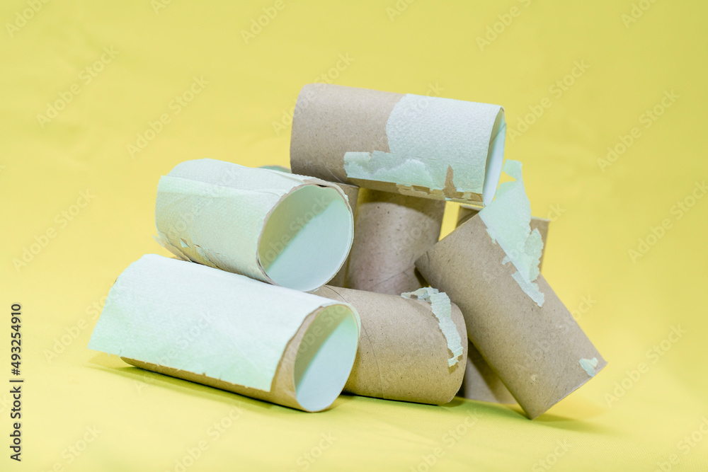 Fototapeta premium A pile of empty toilet paper tubes on a yellowbackground. The concept is a global crisis and a lack of things to meet basic needs.