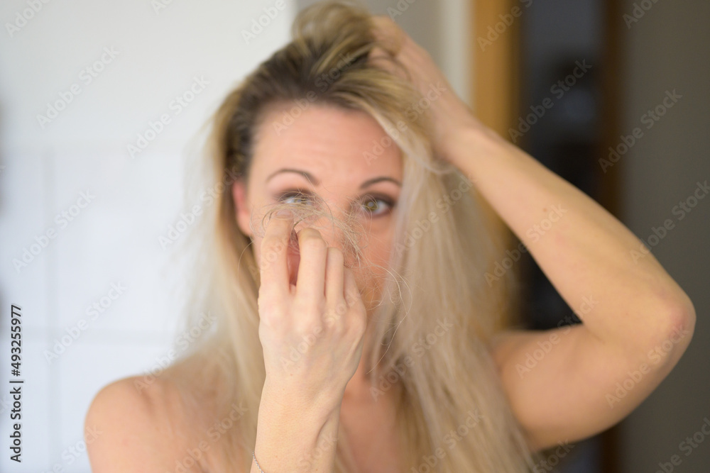 Woman staring in dismay at tufts of loose hair Woman staring in dismay at tufts of loose hair