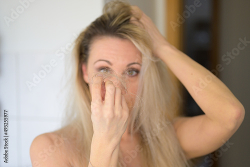 Woman staring in dismay at tufts of loose hair