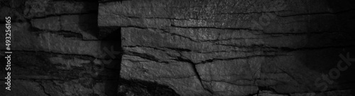 Black and white rock texture. Crushed mountain surface. Close-up. Grunge backdrop. Dark gray stone background with space for design. Wide banner. Panoramic.