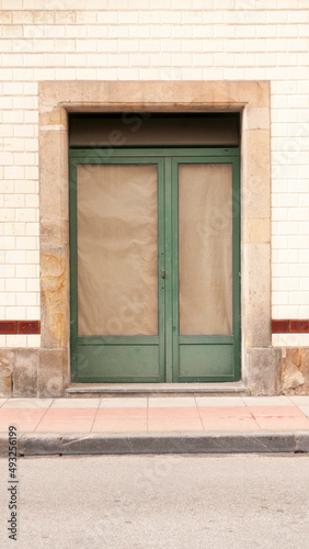 Puerta de tienda clausurada en fachada de baldosas blancas