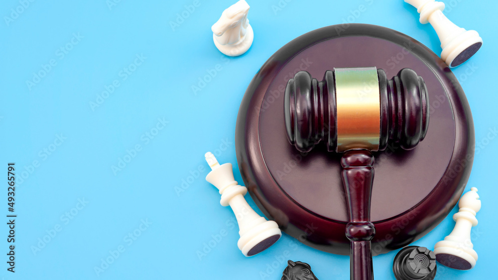 Strategic lawsuit settlement, develop legal strategy and planning court challenge concept with judge gavel and chess pieces isolated on blue background with copy space