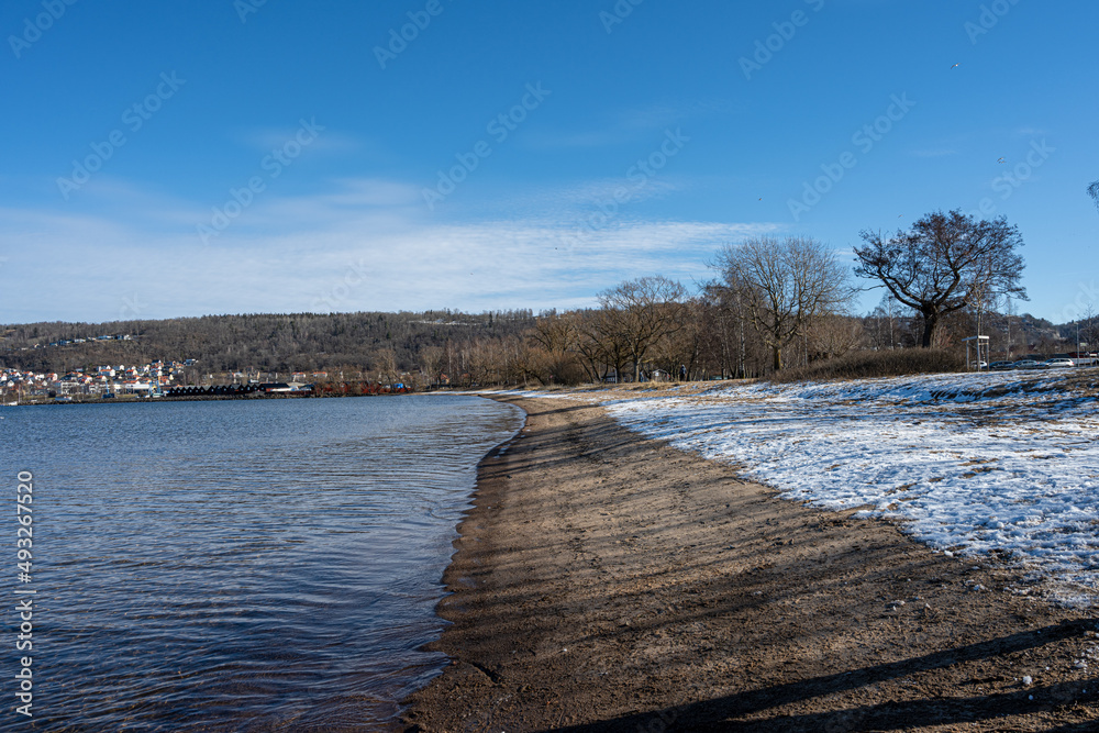 Obraz premium A winter beach covered with snow and a blue sky in the background
