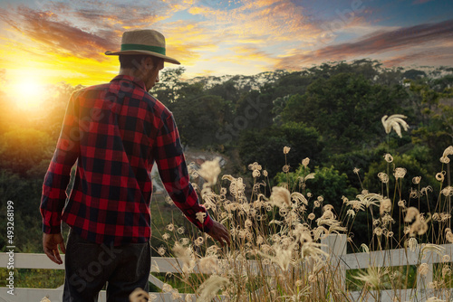 Male young black farmer working in front of the farmers gate.  African Ayoung man in hat at farm with sunset.