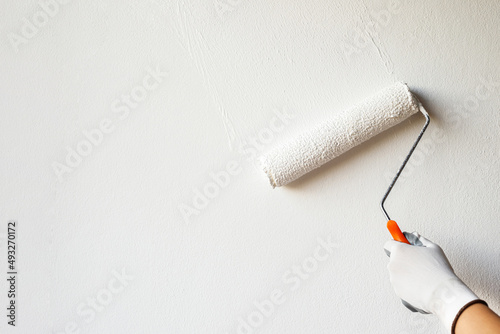 Painter is painting the interior wall white. photo