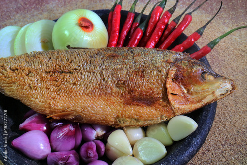 Bandeng Presto Fried Milkfish close up on the mortar with onion slices onion garlic and chili sauce photo