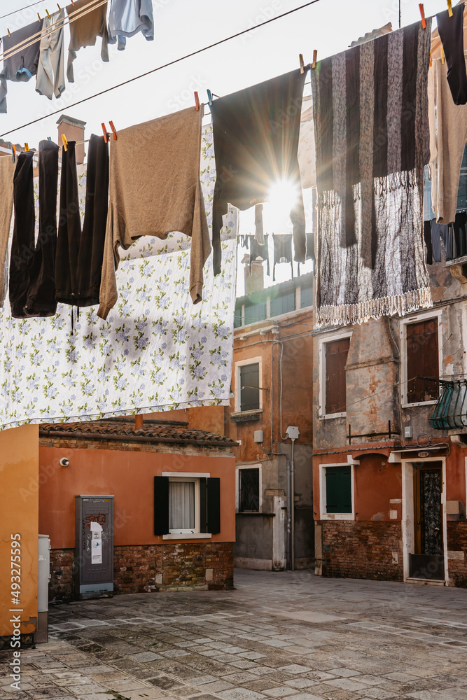 Laundry hanging out of typical Venetian facade,Italy.Narrow street with colorful buildings and clothes dry on rope,Venice.Clean clothes drying outdoors in small square.City lifestyle,urban scene. Laundry hanging out of typical Venetian facade,Italy.Narrow street with colorful buildings and clothes dry on rope,Venice.Clean clothes drying outdoors in small square.City lifestyle,urban scene.