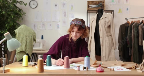 The work of fashion designer and tailors in the shop. Fashion designers working in their studio. Colorful Fabrics, Clothes Hanging and Sewing Items are Visible. photo