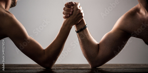 Vászonkép Heavily muscled bearded man arm wrestling a puny weak man