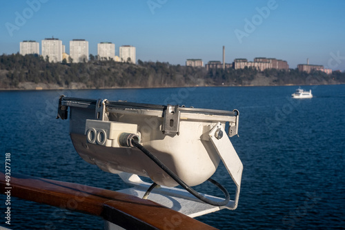 Closeup of a floodlight attached to a railing with Lidingö residential district in the background. photo