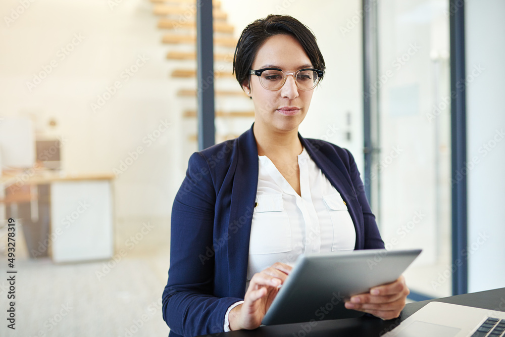 Fine-tuning some plans online. Cropped shot of a young businesswoman working on a digital tablet in a modern office. Fine-tuning some plans online. Cropped shot of a young businesswoman working on a digital tablet in a modern office.