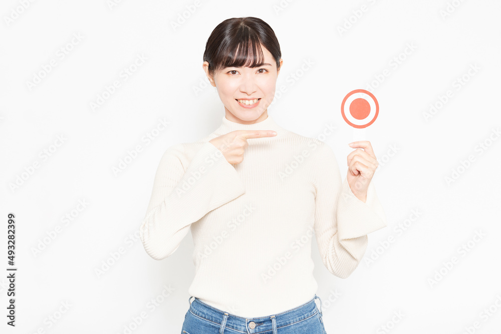 白い背景の前に立ってOKのプラカードを持っている女性