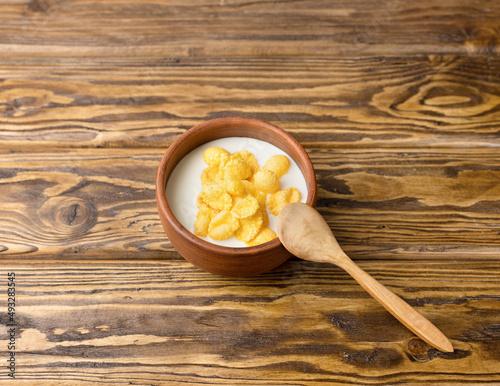 dietary kefir in a ceramic bowl and cornflakes on a wooden background. photo