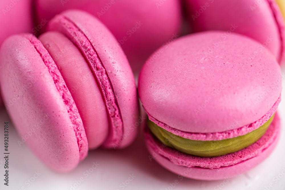 Macarons closeup on white wooden background. Sweet and colourful pink french macaroons. Cooking at home. Macarons closeup on white wooden background. Sweet and colourful pink french macaroons. Cooking at home.