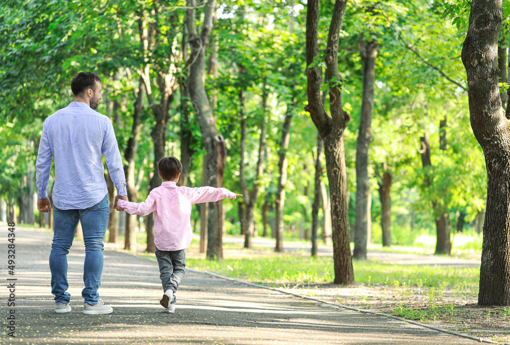 Father walking with his little son in park Father walking with his little son in park