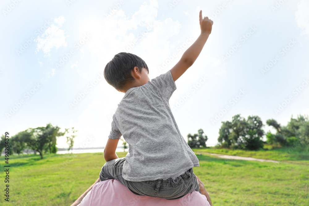Little boy with his father pointing at something in park on sunny day Little boy with his father pointing at something in park on sunny day