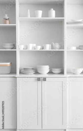Shelf unit with set of clean dishes in kitchen