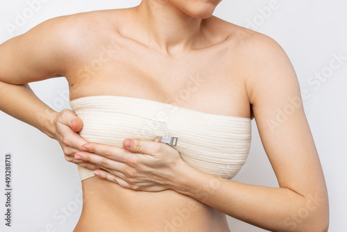 Bild auf Leinwand Cropped shot of young woman with elastic bandage after breast augmentation with silicone implants isolated on white background