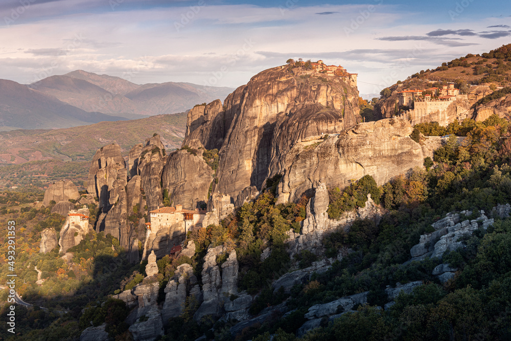 Panoramic scenic view of the famous Meteora floating monasteries on steep cliffs in Greece at sunrise. A journey to the wonders of the world. Visit tourist attractions and landmarks