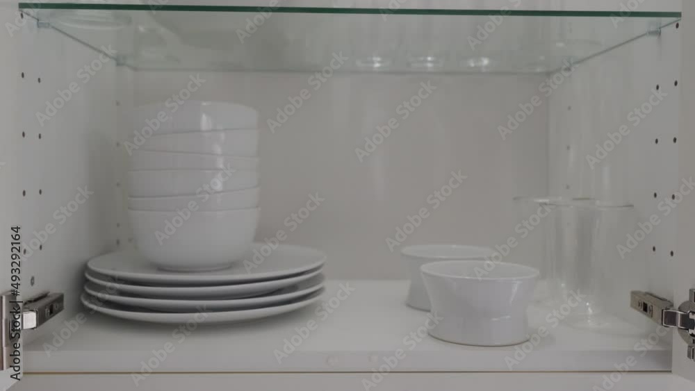 Opening closing the kitchen cabinet glass door with crockery shelves illuminated from the inside. Closeup details of kitchen furniture. High quality 4k footage Opening closing the kitchen cabinet glass door with crockery shelves illuminated from the inside. Closeup details of kitchen furniture. High quality 4k footage