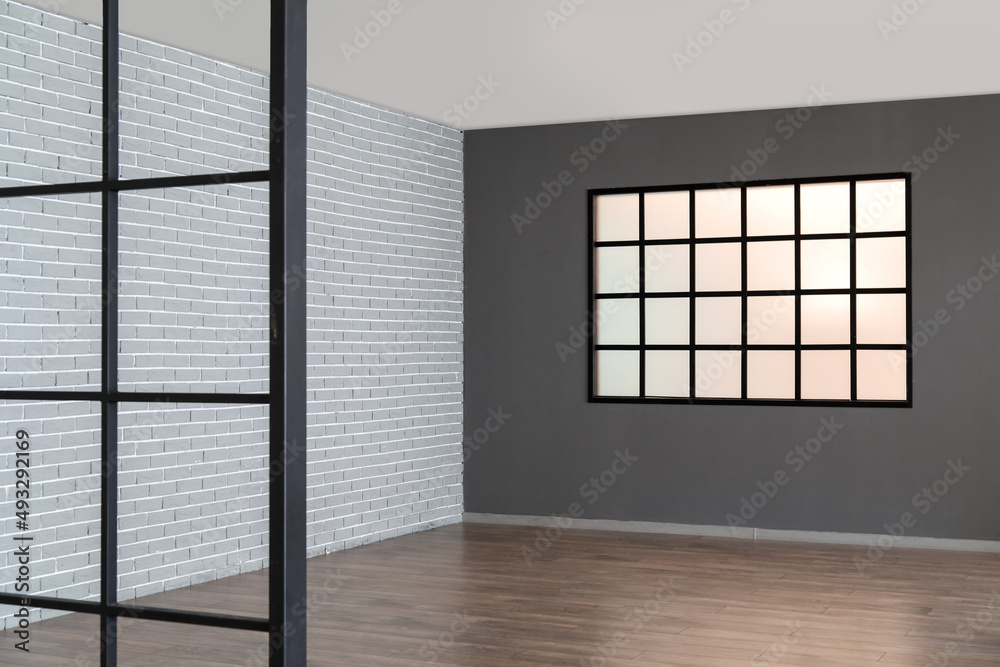 View of big empty room with dark wall and window View of big empty room with dark wall and window