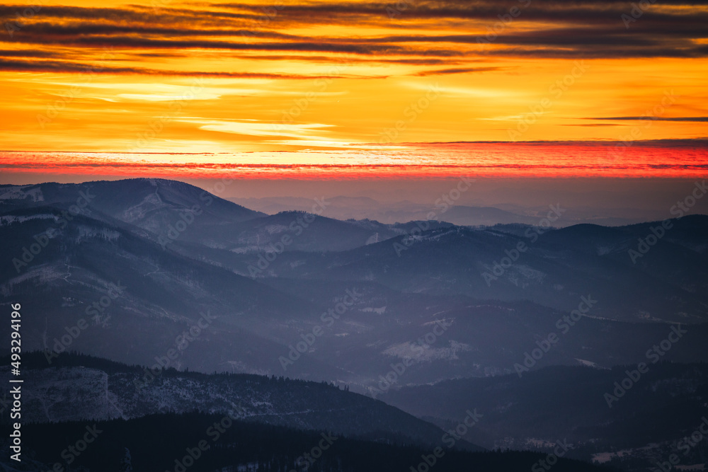 Winter sunset seen from Pilsko in Beskid Żywiecki. Beautiful views of the Tatras and the Mala Fatra massif, bathed in golden light.