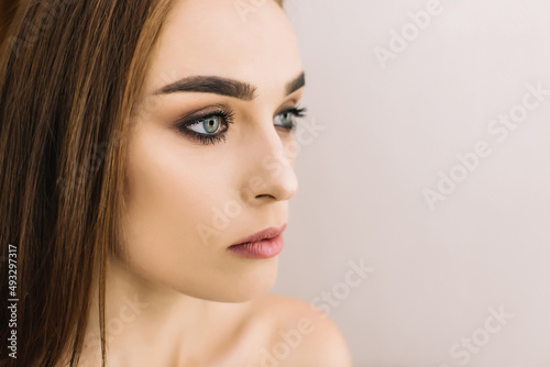 Close up fashion photo of beautiful young woman with dark straight hair and evening make up