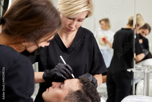 Plastic surgeon preparing for operation on man face photo