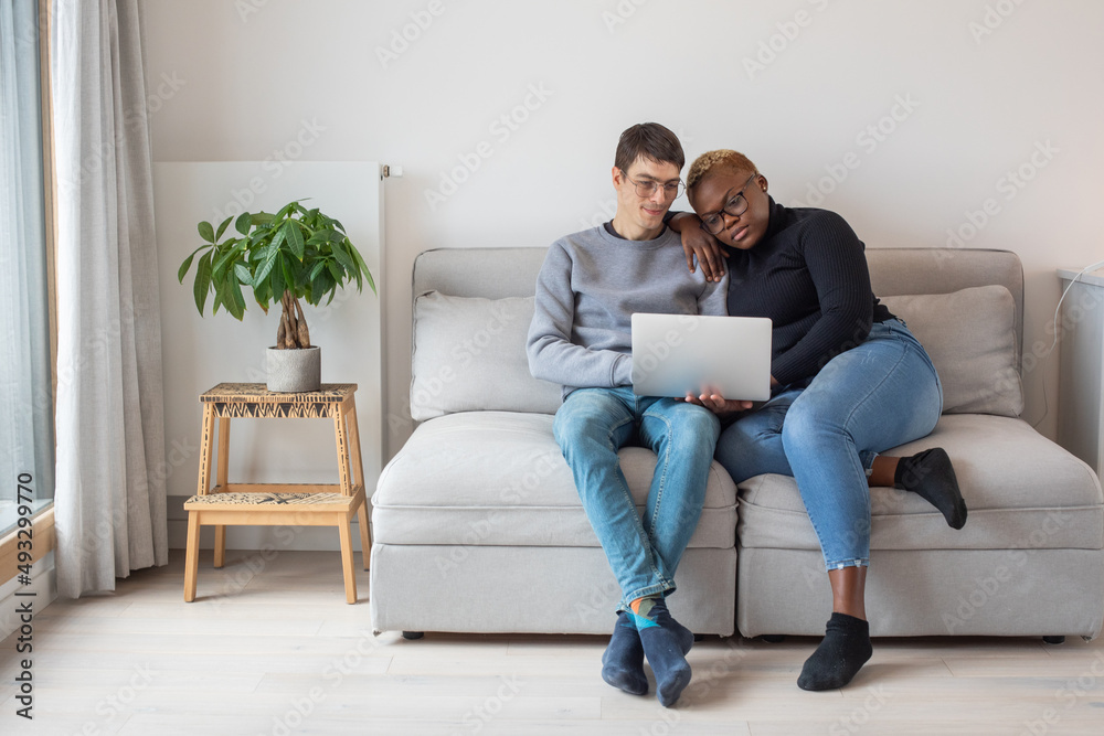 mixed couple using laptop computer at home on couch mixed couple using laptop computer at home on couch