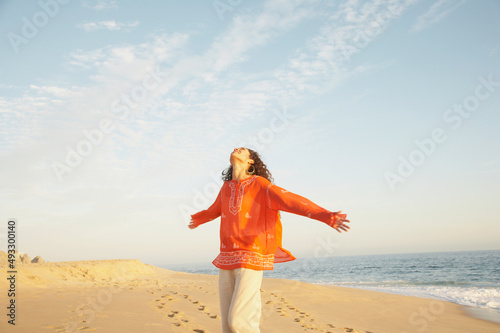 Joyful woman with arms extended on beach on vacation