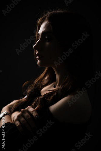 Sexy silhouette of a beautiful girl on a dark plain background. Portrait.