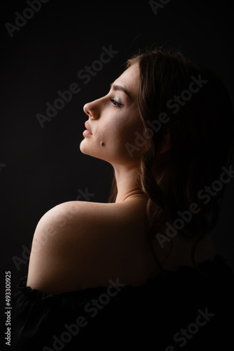 Sexy silhouette of a beautiful girl on a dark plain background. Portrait.