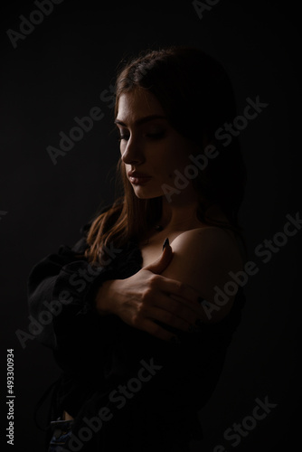 Sexy silhouette of a beautiful girl on a dark plain background. Portrait.