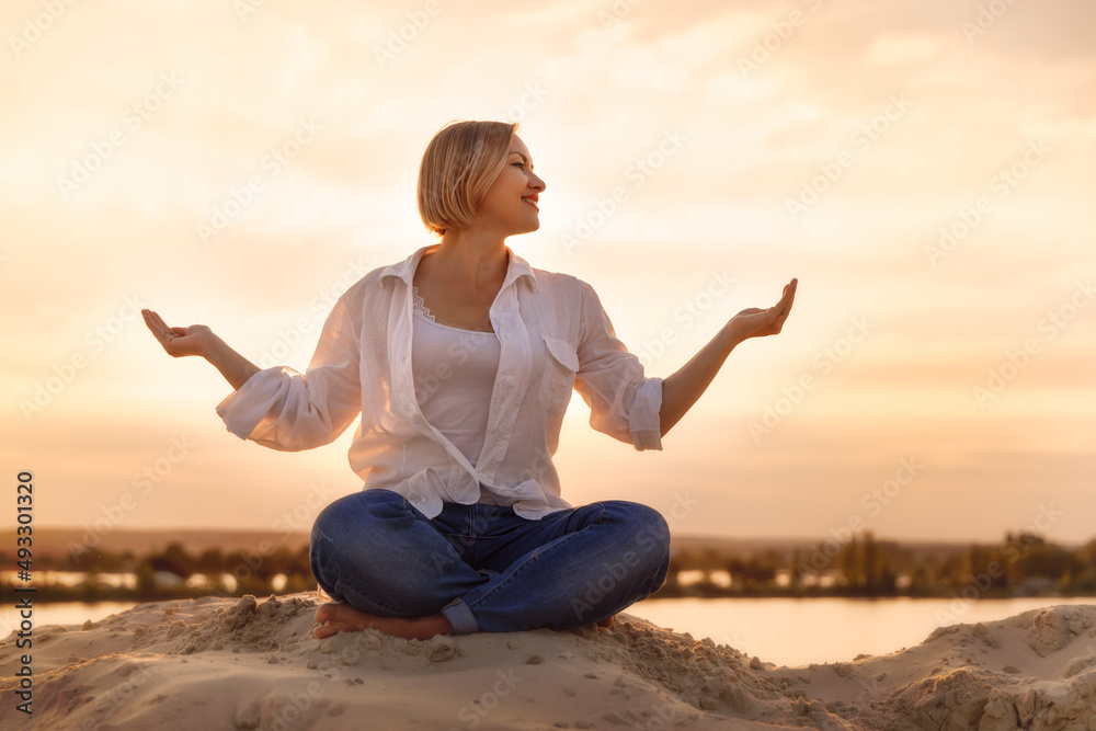 Woman meditating in lotus pose on the beach at sunset Woman meditating in lotus pose on the beach at sunset