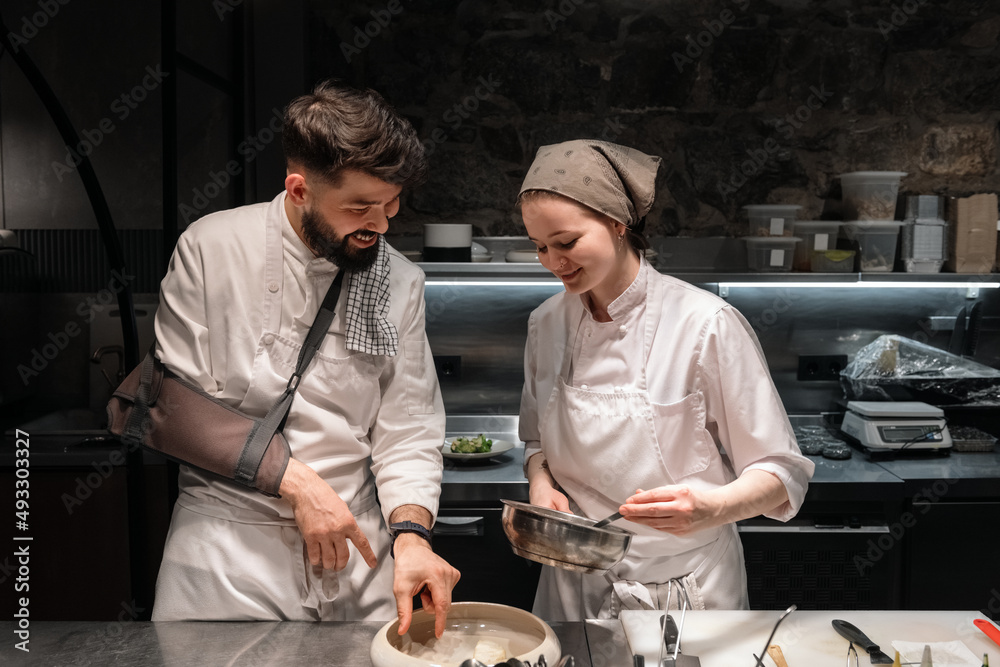 Male chef teaching assistant to cook dish Male chef teaching assistant to cook dish