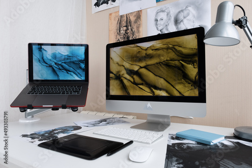 Computer monitor and laptop on artist desk