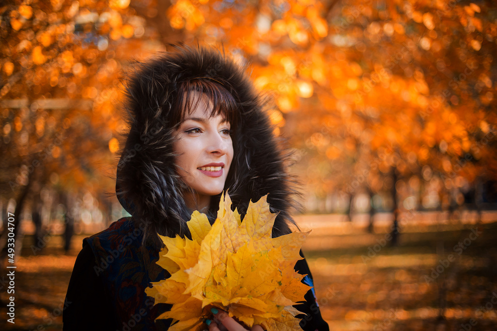 A woman with long black hair in the autumn forest holds a bouquet of maple leaves in her hands. A woman with long black hair in the autumn forest holds a bouquet of maple leaves in her hands.