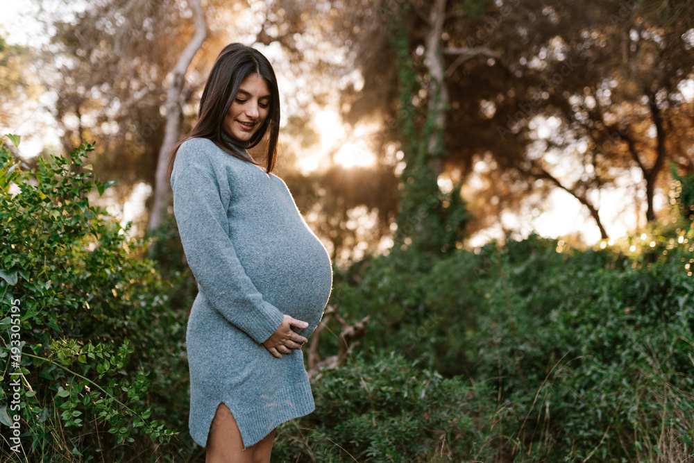 © Ezequiel Giménez/Stocksy - Smiling ethnic pregnant woman touching belly © Ezequiel Giménez/Stocksy - Smiling ethnic pregnant woman touching belly