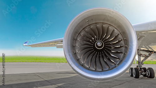 Aircraft jet engine close-up, airplane wing and chassis of landing gear wheel parked at the airport on a sky background, panorama.