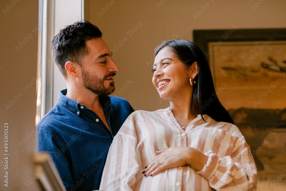 Expectant couple looking at each other smiling at home Expectant couple looking at each other smiling at home