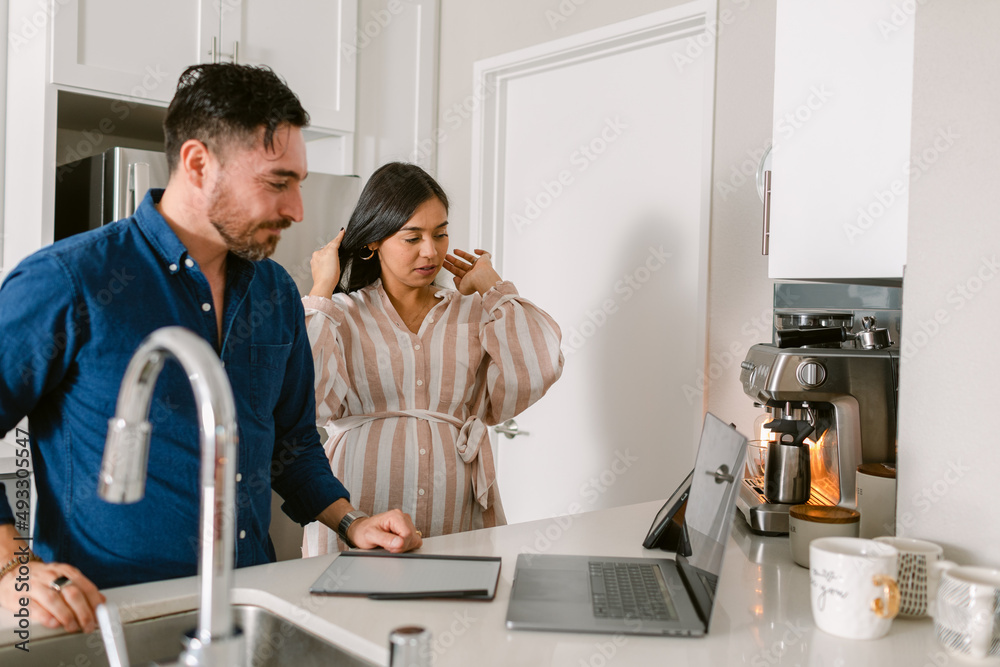 Couple with electronics devices in kitchen Couple with electronics devices in kitchen