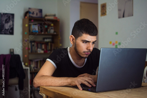 Young latino man at home with pc photo