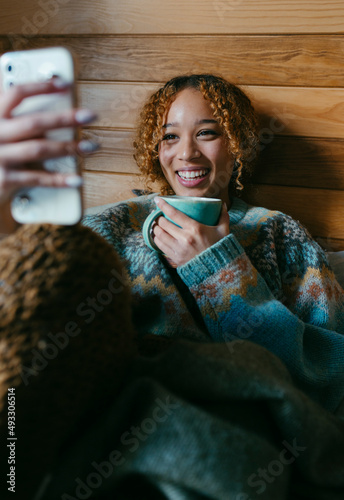 Teenager drinking coffee in bed while video chatting