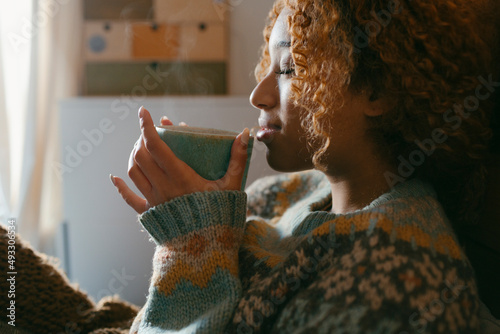 Person drinking hot beverage in cozy bedroom